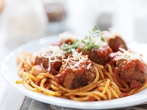 plate of italian spaghetti and meatballs with oregano garnish shot close up