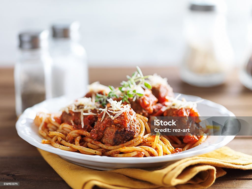 spaghetti and meatballs spaghetti and meatballs with oregano garnish on rustic table shot with selective focus Spaghetti Stock Photo