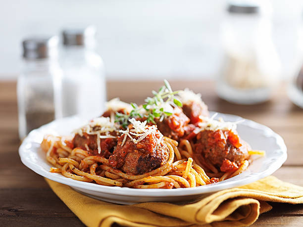 spaghetti and meatballs spaghetti and meatballs with oregano garnish on rustic table shot with selective focus italian food stock pictures, royalty-free photos & images