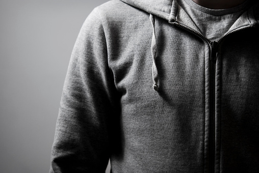 Close up of a grey zip top hoodie in high contrast.