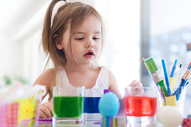 istock Litte girl painting easter eggs 516956962