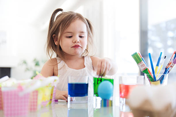 istock Litte girl painting easter eggs 516957020