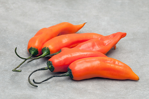 Group of aji amarillo hot chili peppers on stone background.