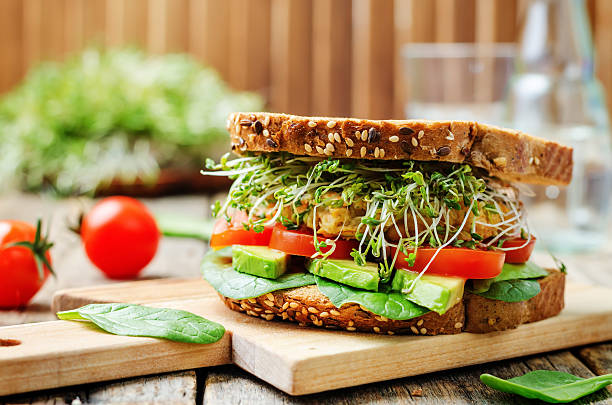 rosenkohl avocado-tomaten-sandwich mit spinat kichererbsen burger roggen - sandwich stock-fotos und bilder