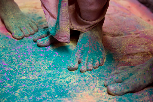 Low section view of a man celebration Holi. The colorful festival of Holi is celebrated on Phalgun Purnima which comes in February end or early March. Holi festival has an ancient origin and celebrates the triumph of 'good' over 'bad'. The colorful festival bridges the social gap and renew sweet relationships. On this day, people hug and wish each other 'Happy Holi'.