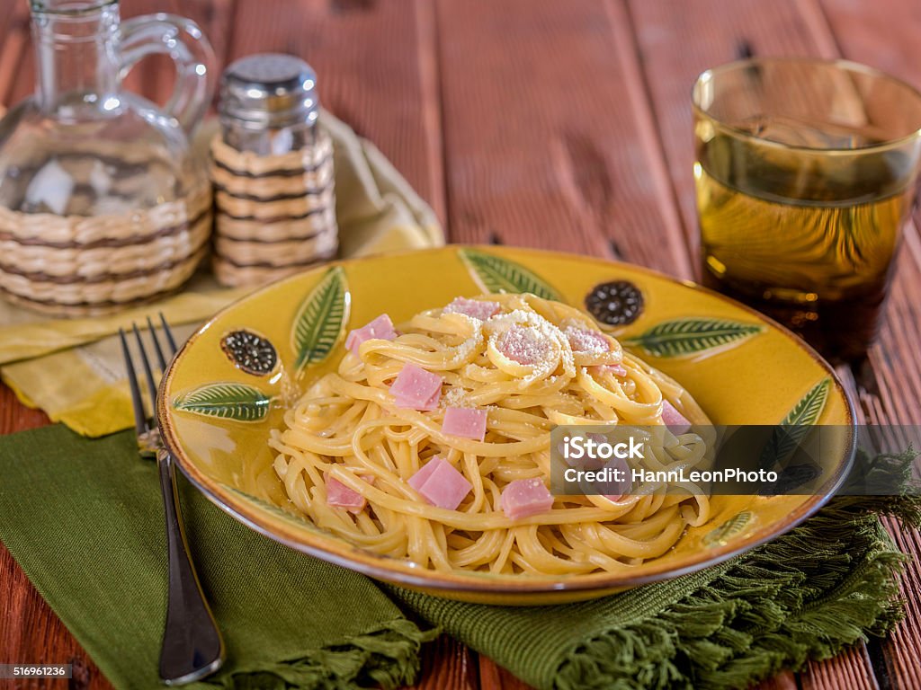 Fettuccine Alfredo Plate of Fettucine Alfredo with pieces of ham on ceramic plate on wooden table top. Baking Stock Photo