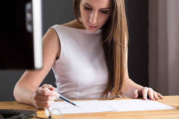 istock Beautiful woman looking at contract at the desk 516962434