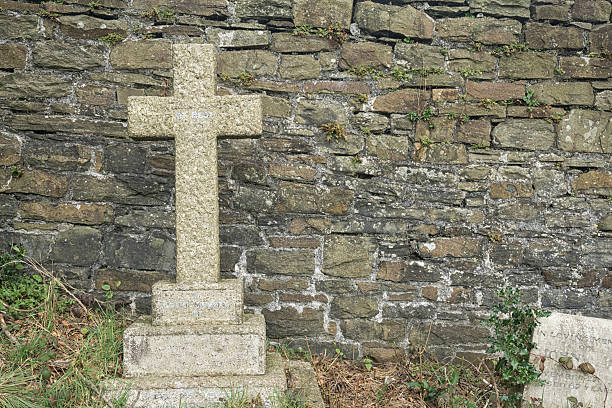 istock Lonely grave cross against an old stone wall 516977258