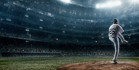 A moment of baseball game  on a baseball stadium under dramatic stormy skies and rain.