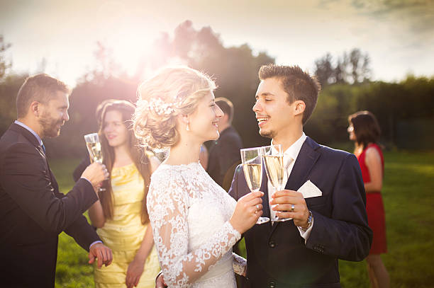 istock Newlyweds and wedding guests clinking glasses 516984529