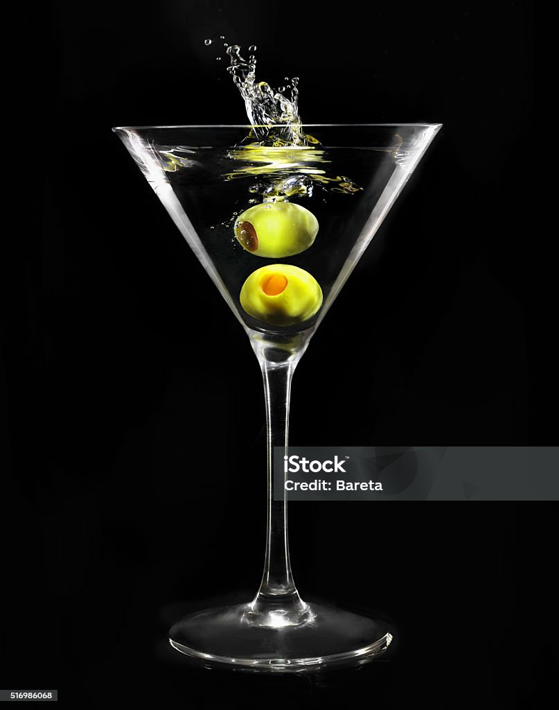 Martini glass Splashing green olive in martini glass on black background Backgrounds Stock Photo