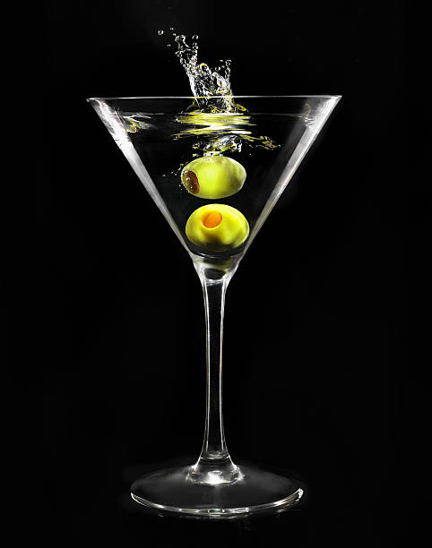 Martini glass Splashing green olive in martini glass on black background martini glass photos stock pictures, royalty-free photos & images