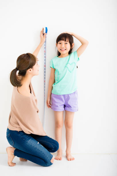 mãe medidas o crescimento de sua filha - measuring child instrument of measurement wall - fotografias e filmes do acervo