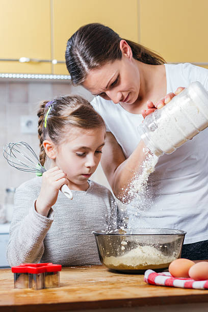 istock Mother and daughter pouring flour into bowl 516991328