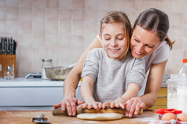 istock Mother and daughter rolling dough with rolling pin 517005080