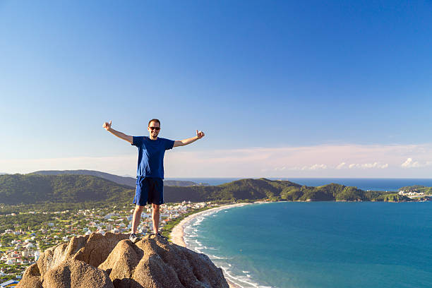 Young man on top of a mountain at Bombinhas - Santa Catarina - Brazil.