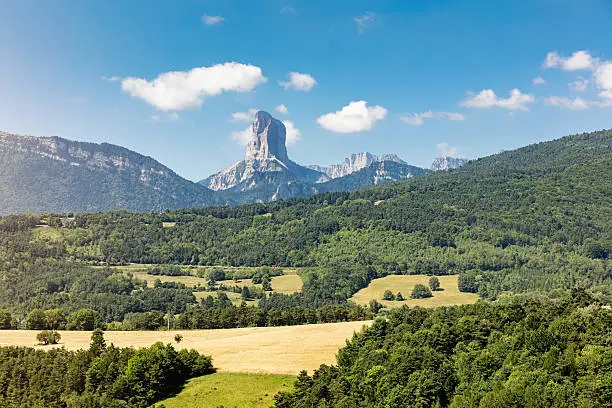 Beautiful summer landscape around the Vercors Plateau of the French Prealps. View to Mont Aiguille (2085m high), known as one of the Seven Wonders of Dauphine. Mont Aiguille is a limestone mesa surrounded by steep cliffs and is very popular for climbers. Vercors National Park Plateau, Isère, Rhone-Alpes, France