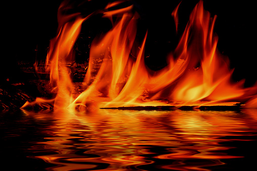 Picturesque flames from a fire on a black background with reflection in water