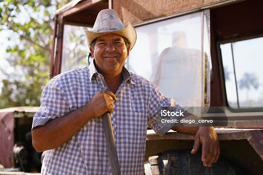 Retrato de hombre feliz agricultor apoyarse en Tractor observando a la cámara - Foto de stock de Etnia Latinoamericana libre de derechos