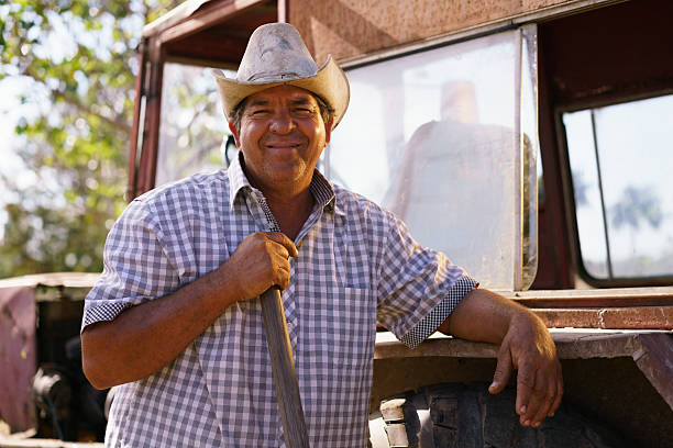 Portrait Happy Man Farmer Leaning On Tractor Looking At Camera