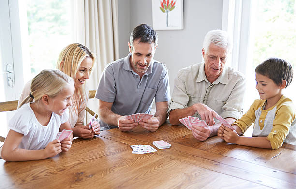 Family fun Shot of a happy three-generational family playing cards together family playing card game stock pictures, royalty-free photos & images