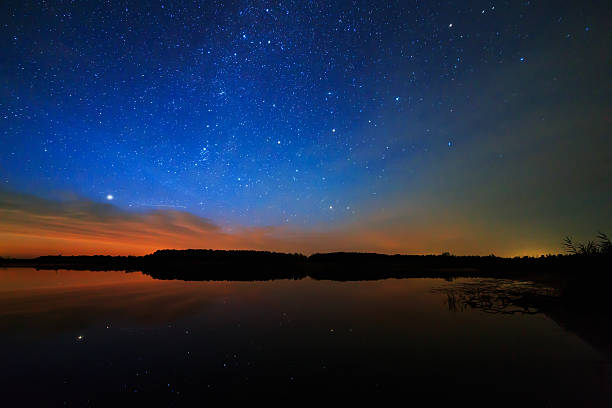 istock Morning dawn on starry background sky reflected in the water 517016345