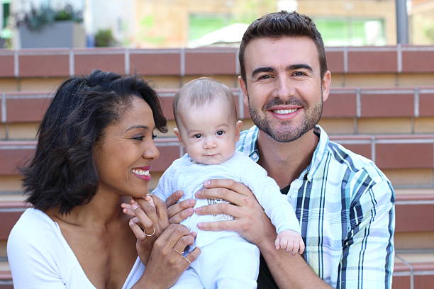 istock Interracial couple embracing with their newborn 517016712