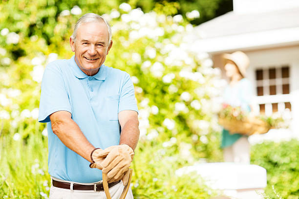 istock Confident Senior Man Holding Gardening Fork While Woman Gardenin 517017029