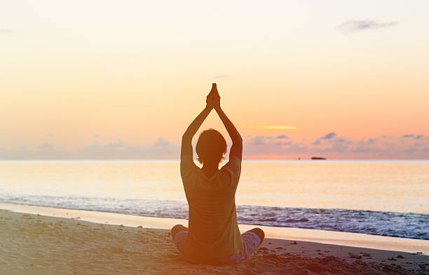 istock Silhouette of young man doing yoga at sunset 517017238
