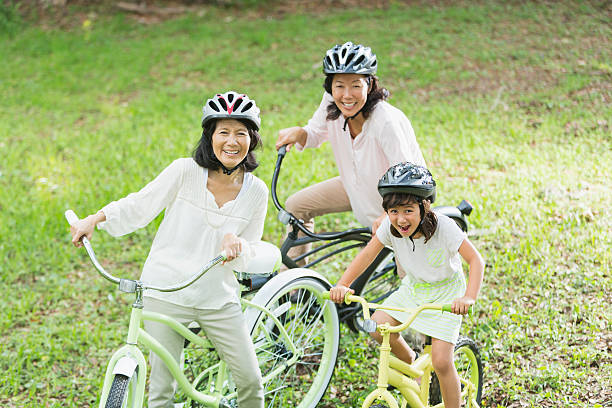 Asian girl (6 years) with mother (40s) and grandmother (60s), riding bicycles.