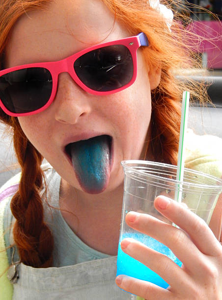 Girl drinking slushie drink with straw, frozen ice-drink, blue tongue