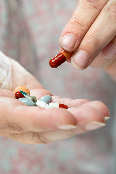 istock Older women pouring medicine into hand. 517019275