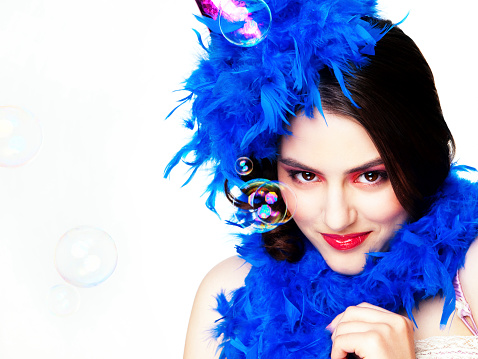 Portrait of the young beautiful woman with a  blue feather boa on a white background.
