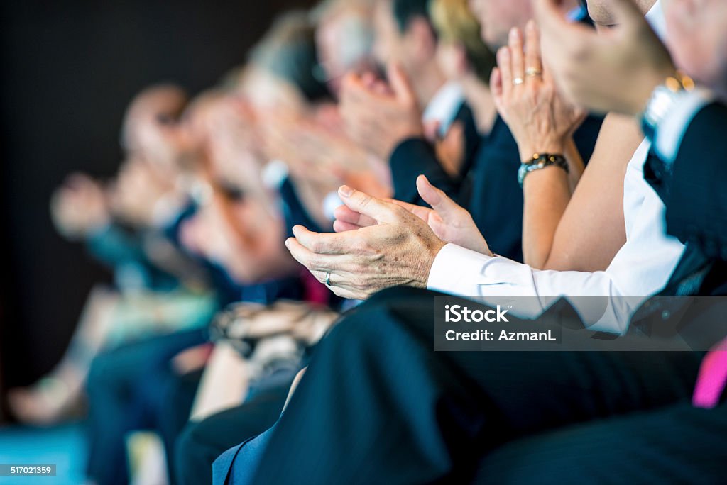 Businesspeople applauding Group of businesspeople sitting in a row and applauding at seminar. Convention Center Stock Photo
