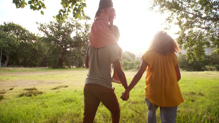 African-american family walking together in beautiful green park