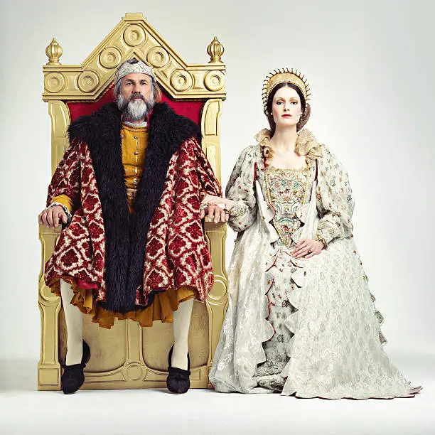 Studio shot of a king and queen sitting on thrones