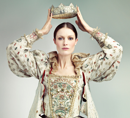 Shot of queen holding a crown over her head