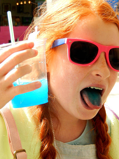 Girl drinking slushie drink with straw, frozen ice-drink, blue tongue