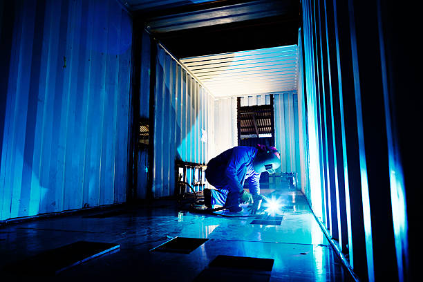 istock Welder working to modify container in steel fabrication plant 517042057