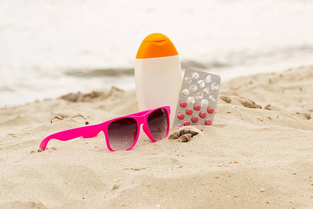 Pink sunglasses, shells, lotion and pills of vitamin E stock photo