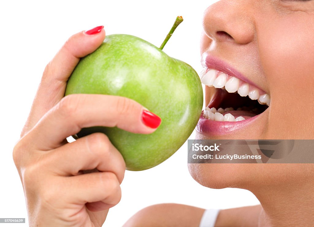 closeup of woman eating a green apple closeup of the face of a woman eating a green apple, isolated against white background Apple - Fruit Stock Photo