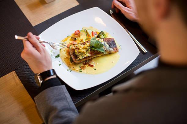 istock Man eating grilled salmon at restaurant 517048274