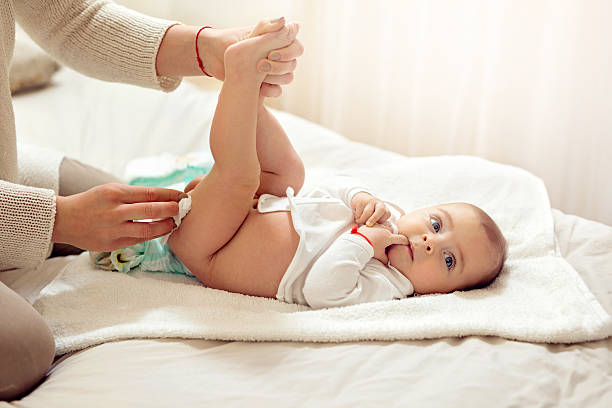 Cute baby boy getting his diaper changed in bedroom. Unrecognizable mother changing baby's diaper on the bed. 2 5 months photos stock pictures, royalty-free photos & images