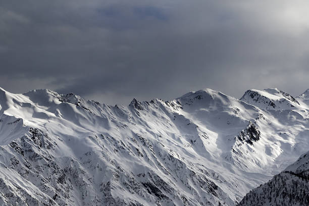 istock High snowy mountains and sunlight storm sky in evening 517053014