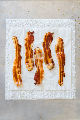 Fried crisp steaky bacon lying on the white paper towel to drain the fat