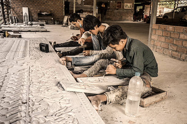 Child labour Cambodia Siem Reap, Сambodia - February 24, 2016: Group of children working and carving stone in a small town near Siem Reap. Child labour is still very common in Cambodia child labor stock pictures, royalty-free photos & images