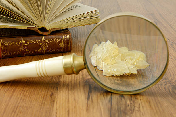 science with Loupe mineral and old book. nature science, watching crystal mineral with Loupe. old nature book open in background calcite stock pictures, royalty-free photos & images