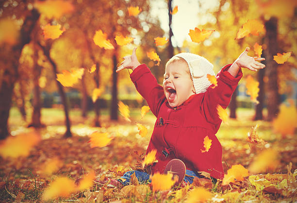 Photo of happy little child, baby girl laughing and playing in autumn