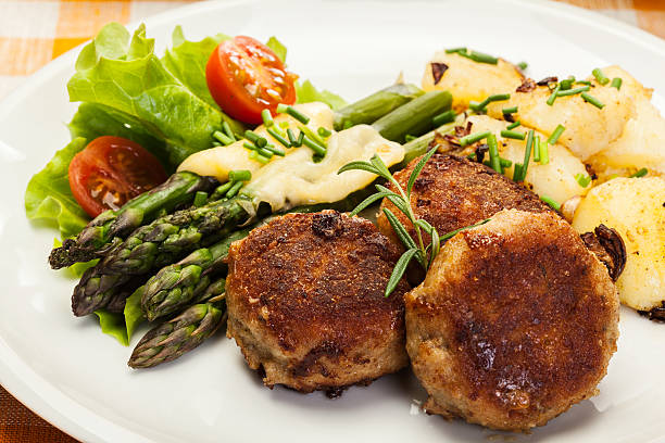 Meatballs served with boiled potatoes and asparagus on a plate