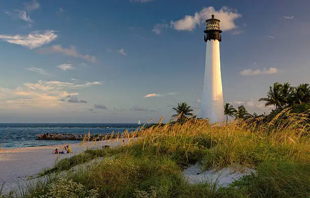 Photo of People have a rest on a beach, near a  Lighthouse.